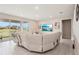 Bright living room featuring a large white sofa, tile floors, and a large window overlooking a lake at 16709 Barnwood Pl, Bradenton, FL 34211