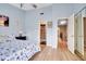 Light blue bedroom with wood floors boasts a ceiling fan, ensuite bathroom, and hall access at 17960 Gulf Blvd # 104, Redington Shores, FL 33708