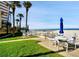 Outdoor patio area with tables, chairs, and umbrellas overlooking the beautiful sandy beach at 17960 Gulf Blvd # 104, Redington Shores, FL 33708
