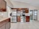 Well-lit kitchen featuring stainless steel appliances, wooden cabinets, and access to sliding glass doors at 1969 Wolf Laurel Dr, Sun City Center, FL 33573