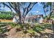Backyard view showcasing the screened-in lanai attached to the home, surrounded by lush landscaping at 3004 Rolling Acres Pl, Valrico, FL 33596