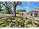 Well-maintained backyard showcasing a large tree, white fence, and screened patio at 3004 Rolling Acres Pl, Valrico, FL 33596