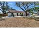 Well-maintained single-story house with white brick, a brown roof, mature trees, and a driveway at 3004 Rolling Acres Pl, Valrico, FL 33596