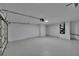 Spacious two-car garage with painted floor, a single overhead light, and side entry door at 3004 Rolling Acres Pl, Valrico, FL 33596