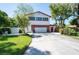 Two-story home featuring red roof, two-car garage, landscaped front yard, and mature trees at 3302 W Caracas St, Tampa, FL 33614