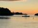 A boat cruising on tranquil waters, silhouetted against the colors of dusk at 3309 Rock Royal Dr, Holiday, FL 34691