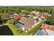 Aerial view of a home with a screened pool and landscaping, set near a pond and mature trees at 3579 Landmark Trl, Palm Harbor, FL 34684