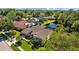 Aerial view of a home with landscaped yard, mature trees, and a nearby pond in an upscale community at 3579 Landmark Trl, Palm Harbor, FL 34684