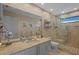 This bathroom is enhanced with a large mirror, granite countertop vanity, and glass door shower at 3579 Landmark Trl, Palm Harbor, FL 34684