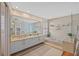 This bathroom features double sinks, a large soaking tub, a glass-enclosed shower, and neutral tiling throughout at 3579 Landmark Trl, Palm Harbor, FL 34684