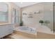 A tiled drop-in tub is framed by plantation shutters and a glass-enclosed shower in this bright bathroom at 3579 Landmark Trl, Palm Harbor, FL 34684