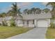 Inviting exterior with metal roof, white facade, front porch, attached garage, and tropical landscaping with palm trees at 3633 Richboro Dr, Holiday, FL 34691