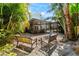 Backyard fire pit area with tropical plants and seating, view of screened patio and pool at 4912 W Bay Way Dr, Tampa, FL 33629