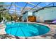 Screened-in pool area with lush landscaping, outdoor shower, dining area, and outdoor lounging at 4912 W Bay Way Dr, Tampa, FL 33629