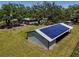 Aerial shot of barn with solar panels, nestled within mature trees and expansive greenery at 5870 Jim Davis Rd, Parrish, FL 34219