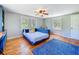 Bedroom featuring wood floors, a blue daybed, two bright windows, and a blue rug at 5870 Jim Davis Rd, Parrish, FL 34219