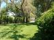 Spacious backyard with lush green grass, mature trees, and a black fence at 6130 Whimbrelwood Dr, Lithia, FL 33547