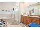 Bright bathroom featuring a soaking tub, glass-enclosed shower, double sink vanity, and neutral tile floors at 6130 Whimbrelwood Dr, Lithia, FL 33547