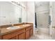 Well-lit bathroom featuring a double sink vanity, large mirror, shower, and neutral tiling at 6130 Whimbrelwood Dr, Lithia, FL 33547
