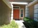 Inviting entrance with a bright orange double door, lush landscaping, and a covered porch area at 6130 Whimbrelwood Dr, Lithia, FL 33547