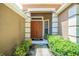 Inviting entryway featuring a solid wood front door, sidelight window, and colorful foliage at 6130 Whimbrelwood Dr, Lithia, FL 33547