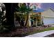 Charming yellow two-story home featuring a well-manicured lawn, palm trees, and an attached two car garage at 6230 Gannetdale Dr, Lithia, FL 33547
