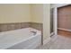 Bathroom with large white tub, travertine tile surround and a shower with glass doors at 6451 Sunset Bay Cir, Apollo Beach, FL 33572