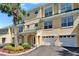 Beautiful townhome features a two-car garage, verdant landscaping, and green awnings at 6451 Sunset Bay Cir, Apollo Beach, FL 33572