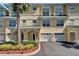 Attractive yellow townhome with green awnings, a two-car garage, and lush landscaping at 6451 Sunset Bay Cir, Apollo Beach, FL 33572