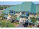 Exterior elevation showcases the yellow facade, green metal roofs, palm trees, and garages at 6451 Sunset Bay Cir, Apollo Beach, FL 33572