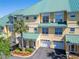 Exterior view of the townhome featuring a green metal roof, two-car garage, and tropical landscaping at 6451 Sunset Bay Cir, Apollo Beach, FL 33572