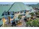 Exterior view of the townhome highlighting the green metal roof, garages, and lush landscaping at 6451 Sunset Bay Cir, Apollo Beach, FL 33572