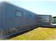 Exterior view of a blue-sided home with a grass lawn and exposed pier and beam at 652 54Th S Ln # 153, Gulfport, FL 33707