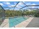 Screened-in pool features a beautiful travertine deck and outdoor lounge with tropical landscaping at 7338 Milestone Dr, Apollo Beach, FL 33572