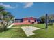 Backyard of a salmon-colored home featuring a small concrete patio, a screened-in porch and palm trees at 763 182Nd E Ave, Redington Shores, FL 33708