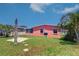 Backyard of a salmon-colored home featuring a small concrete patio, a screened-in porch and palm trees at 763 182Nd E Ave, Redington Shores, FL 33708