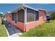 View of enclosed porch on salmon-colored home featuring screened windows covered with blue and yellow striped curtains at 763 182Nd E Ave, Redington Shores, FL 33708