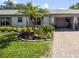 Charming single-story home with lush tropical landscaping, palm trees and paved driveway at 8244 Brentwood Rd, Seminole, FL 33777
