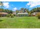 Backyard view of a green two-story home with a screened patio, set on a lush lawn under a partly cloudy sky at 9603 Sunnyoak Dr, Riverview, FL 33569