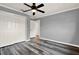 Bedroom features wood floors, light gray walls, white doors, a ceiling fan, and natural light at 9603 Sunnyoak Dr, Riverview, FL 33569