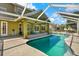 Covered backyard pool with blue tile trim, adjacent to a covered patio area, surrounded by concrete at 9603 Sunnyoak Dr, Riverview, FL 33569