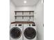 Modern laundry room with front load washer and dryer, wood countertop, and dark shelving at 9920 Spoonbill E Rd, Bradenton, FL 34209