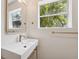 Elegant bathroom boasts a floating sink, brass fixtures, mirror, and a window framing a tropical view at 108 5Th St, Belleair Beach, FL 33786