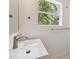 Stylish bathroom with a modern sink, brass fixtures, and a window with a view of lush greenery at 108 5Th St, Belleair Beach, FL 33786