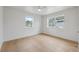 A bright bedroom with two windows, light wood floors and white ceiling fan at 108 5Th St, Belleair Beach, FL 33786