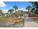 Charming single-story home with a green front door and palm trees in the landscaped yard at 108 5Th St, Belleair Beach, FL 33786