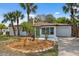 Charming single-story home with lush landscaping, a stone chimney, a green door, and an attached garage at 108 5Th St, Belleair Beach, FL 33786