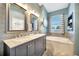 Bathroom with double vanity, gray cabinets, soaking tub, and neutral paint at 10922 Holly Cone Dr, Riverview, FL 33569