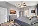 Modern bedroom with gray walls, wood floors, ceiling fan, and dresser with TV above at 10922 Holly Cone Dr, Riverview, FL 33569