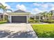 Beautiful home with a well-kept lawn, mature palm trees, and a spacious driveway leading to a two-car garage at 10922 Holly Cone Dr, Riverview, FL 33569